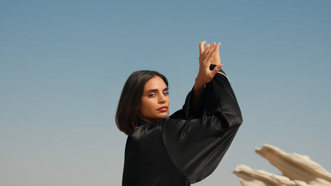 Black satin abaya with flowing sleeves against a desert backdrop