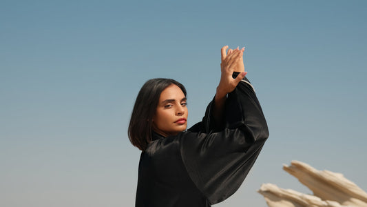 Black satin abaya with flowing sleeves against a desert backdrop