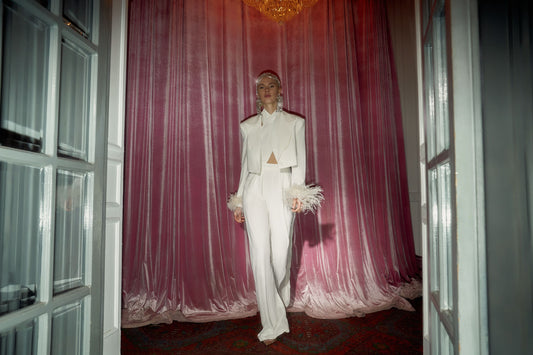 White cropped jacket with feather-trimmed cuffs styled with white trousers
