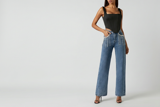 Blue rhinestone jeans styled with a black top and sandals against a grey studio background